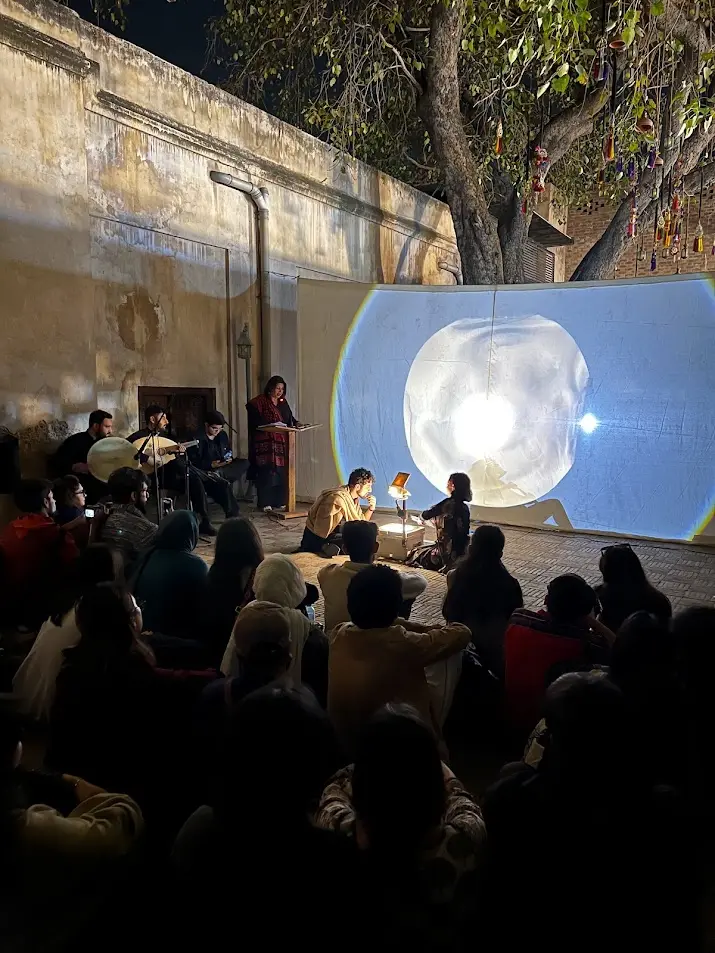 A Sangat evening under a tree, with a screening in the courtyard