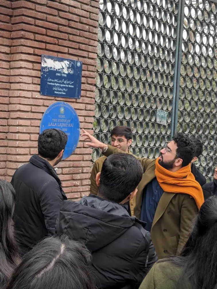 A Lahore ka Ravi Storyteller reading a heritage plaque with a group